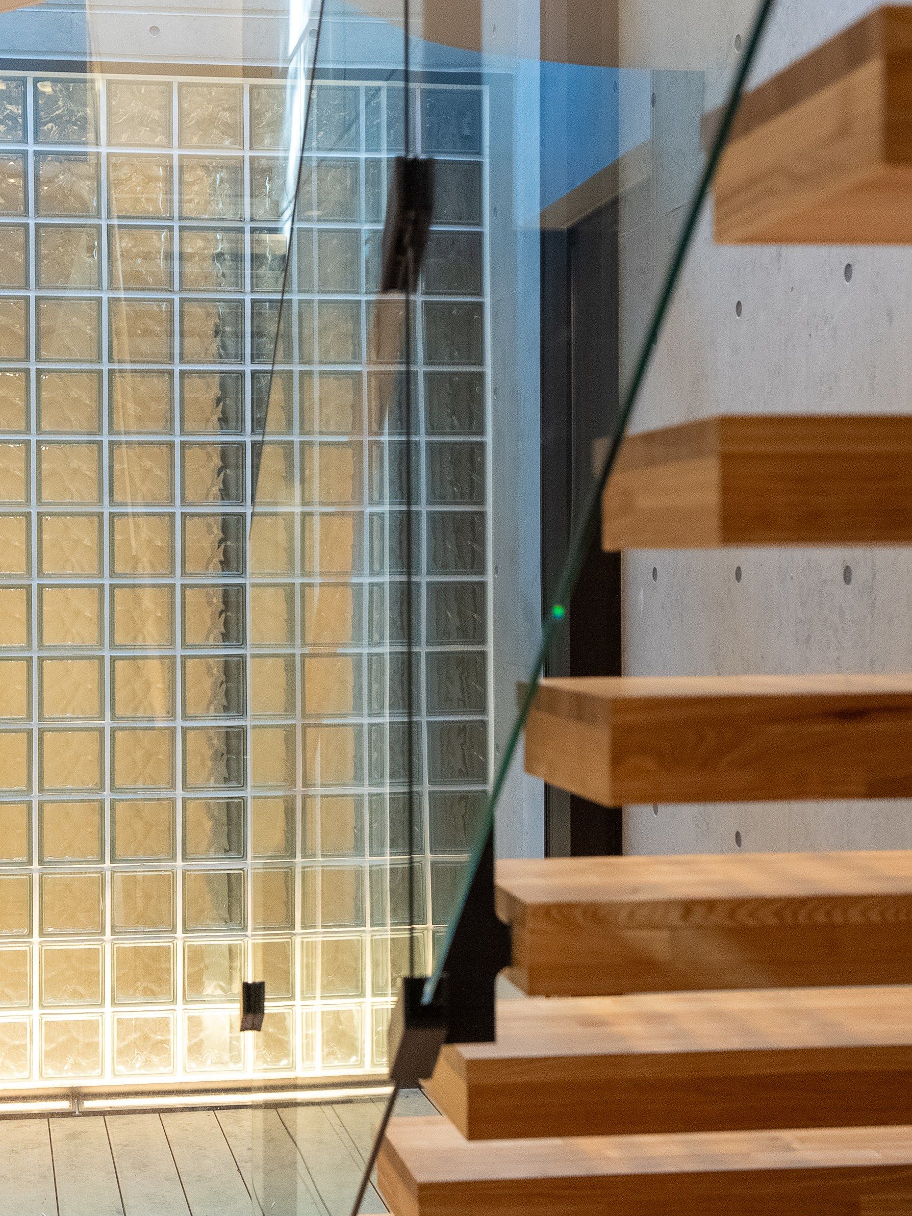 The maisonette stair descending along a wall of board-marked concrete.